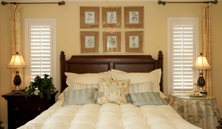 Tall plantation shutters framing bed in a bedroom in Orlando 